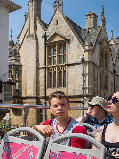 Open-top bus tour in Oxford with historic architecture in the background.
