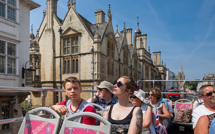 Open-top bus tour in Oxford with historic architecture in the background.
