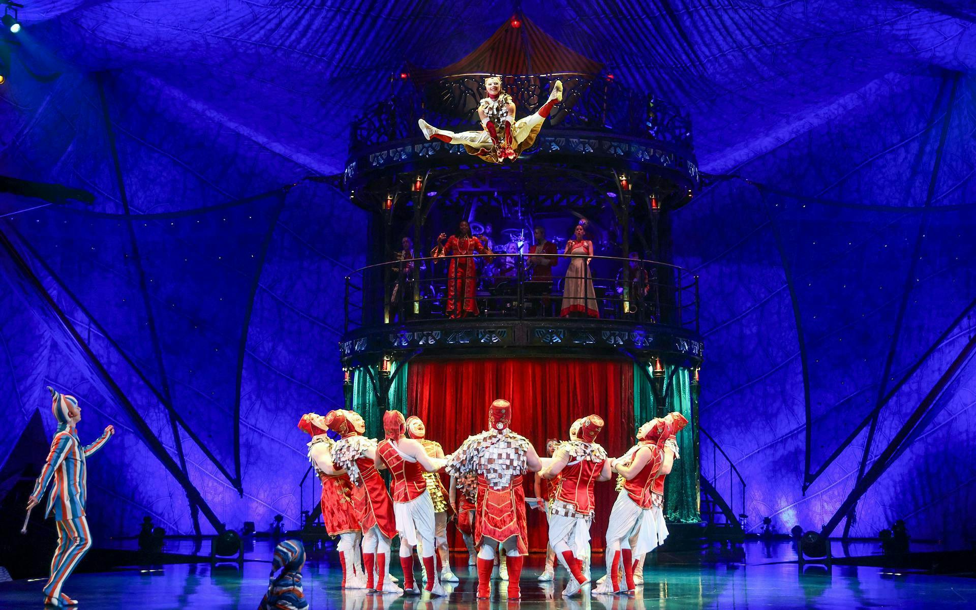 Acrobats performing in Kooza show with vibrant costumes and stage set.
