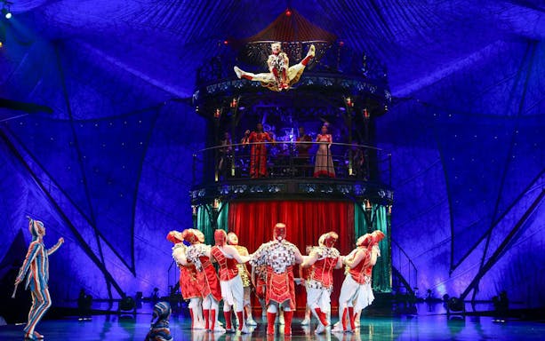 Acrobats performing in Kooza show with vibrant costumes and stage set.