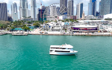 Cruise boat on Biscayne Bay with Miami skyline and Ferris wheel in the background.