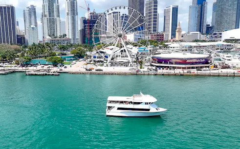 Cruise boat on Biscayne Bay with Miami skyline and Ferris wheel in the background.