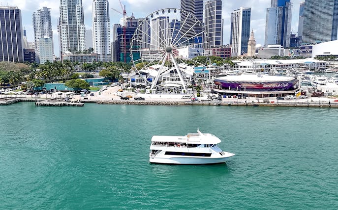 Cruise boat on Biscayne Bay with Miami skyline and Ferris wheel in the background.