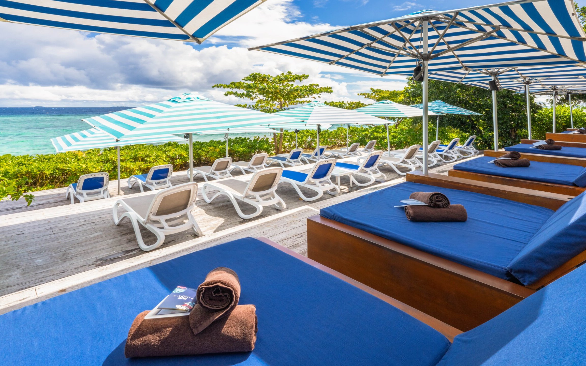 Lounge chairs and umbrellas at Malamala Beach Club, Fiji overlooking the ocean.