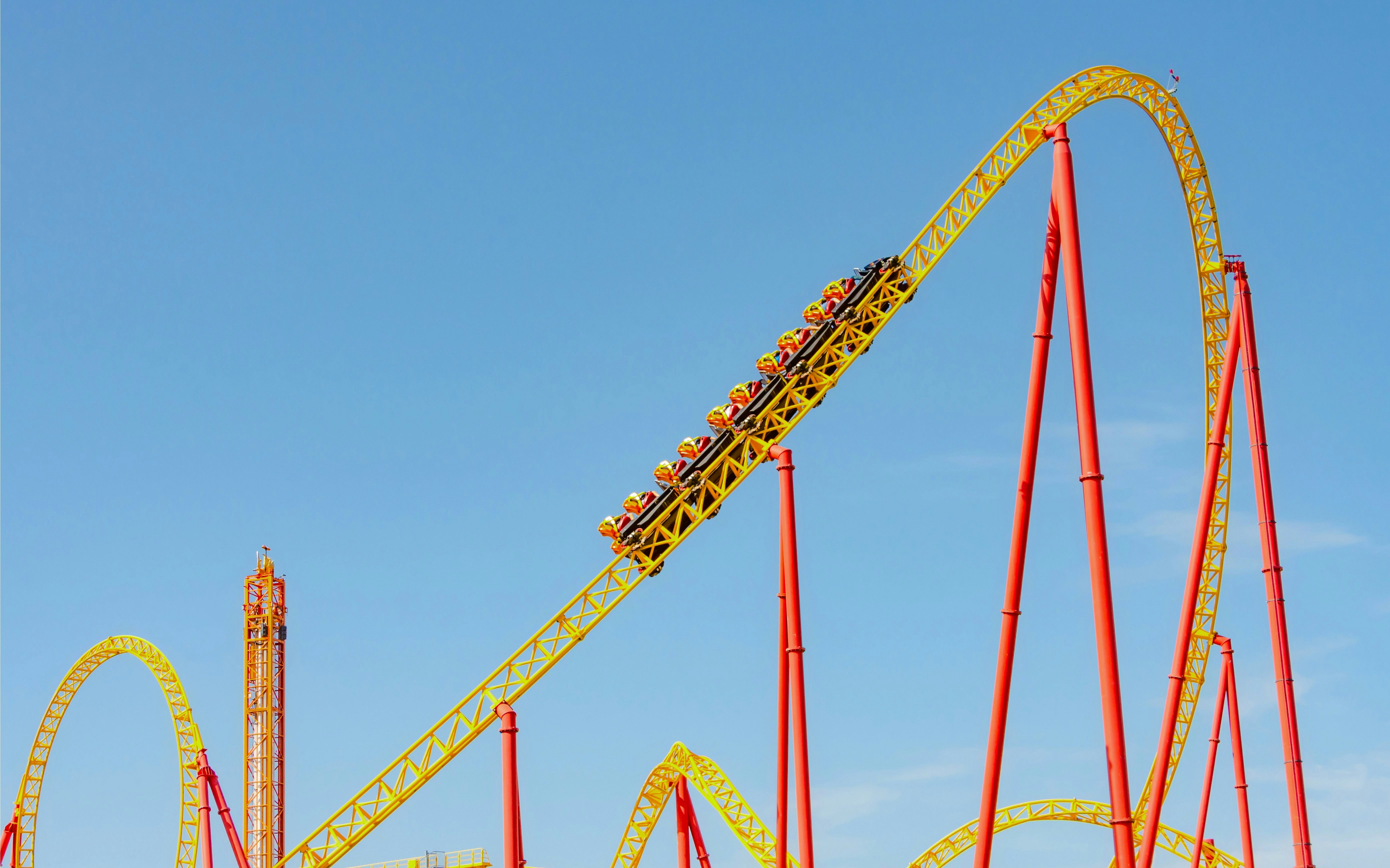 Yellow and red roller coaster with trolleys on a steep turn and loop.