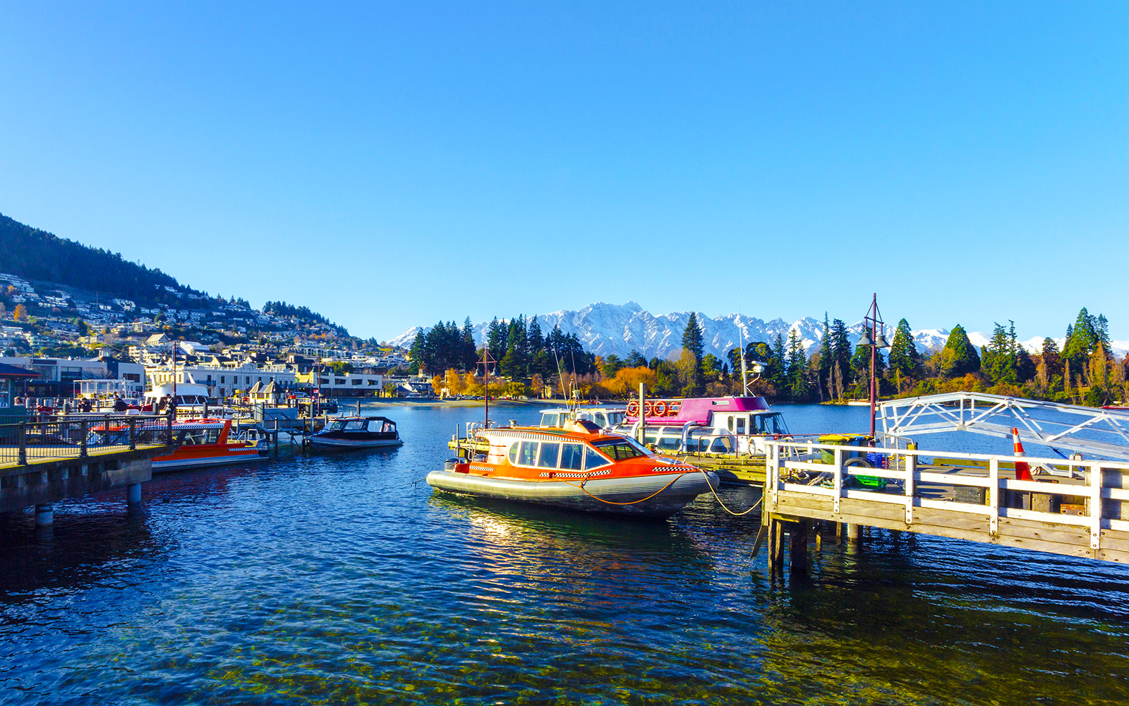 Boats docked at Queenstown Marina with mountains in the background.