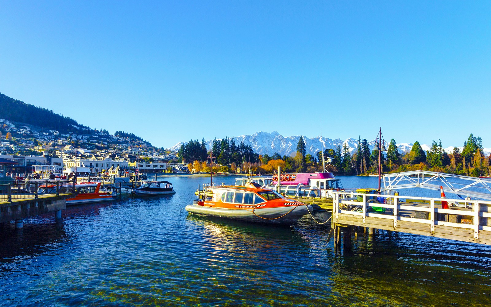 Boats docked at Queenstown Marina with mountains in the background.