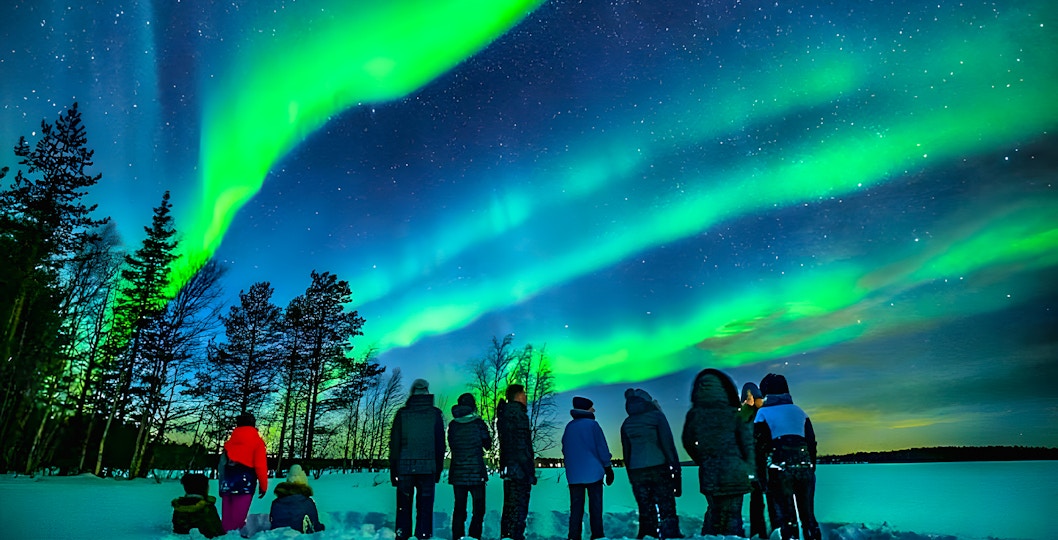 Northern lights over snowy Rovaniemi landscape with group on guided tour.