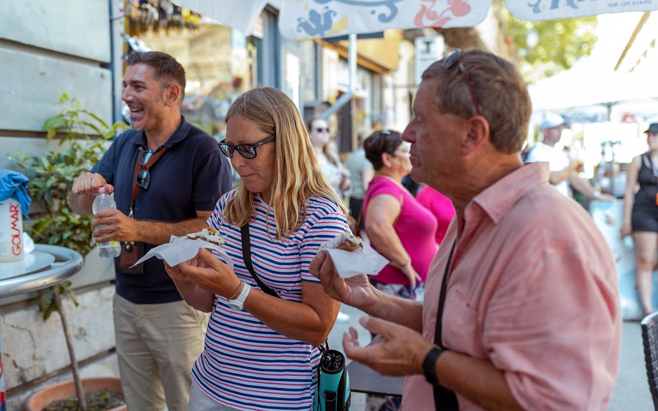 Tourists enjoying street food during UNESCO Sites Walking Tour in Palermo.