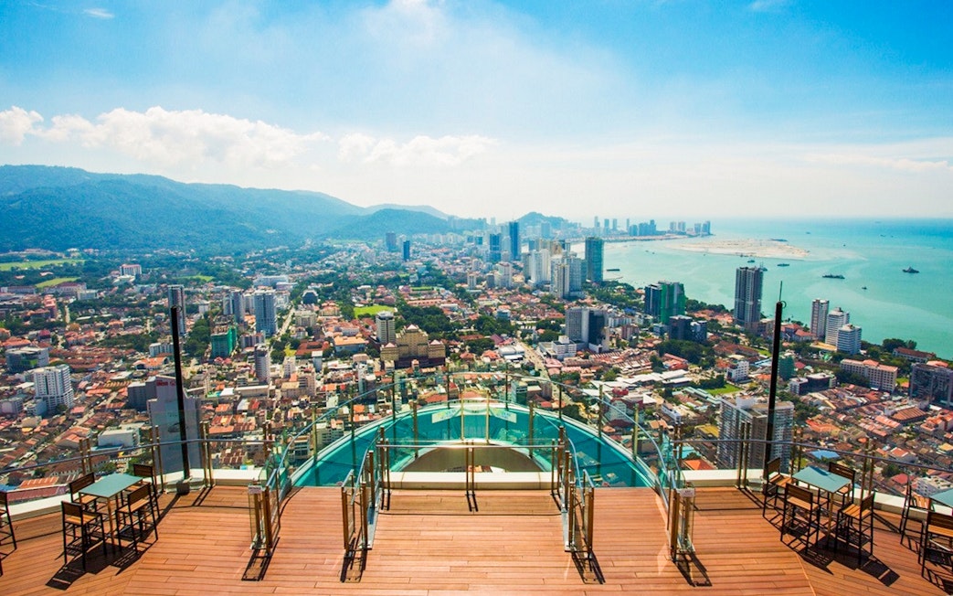 Skywalk view from The Rainbow Walk at The Top, Penang, overlooking cityscape and coastline.