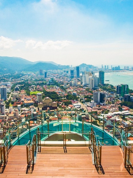 Skywalk view from The Rainbow Walk at The Top, Penang, overlooking cityscape and coastline.