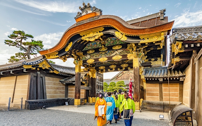 Visitors entering Nijo Castle's ornate main gate in Kyoto, Japan.