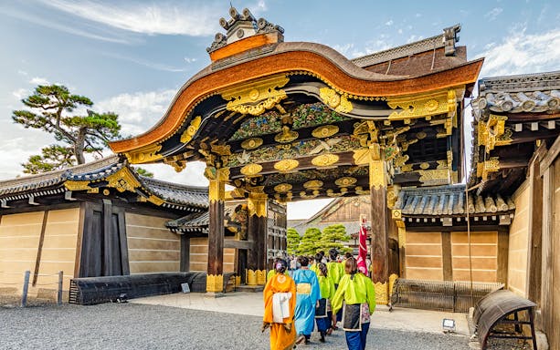 Visitors entering Nijo Castle's ornate main gate in Kyoto, Japan.