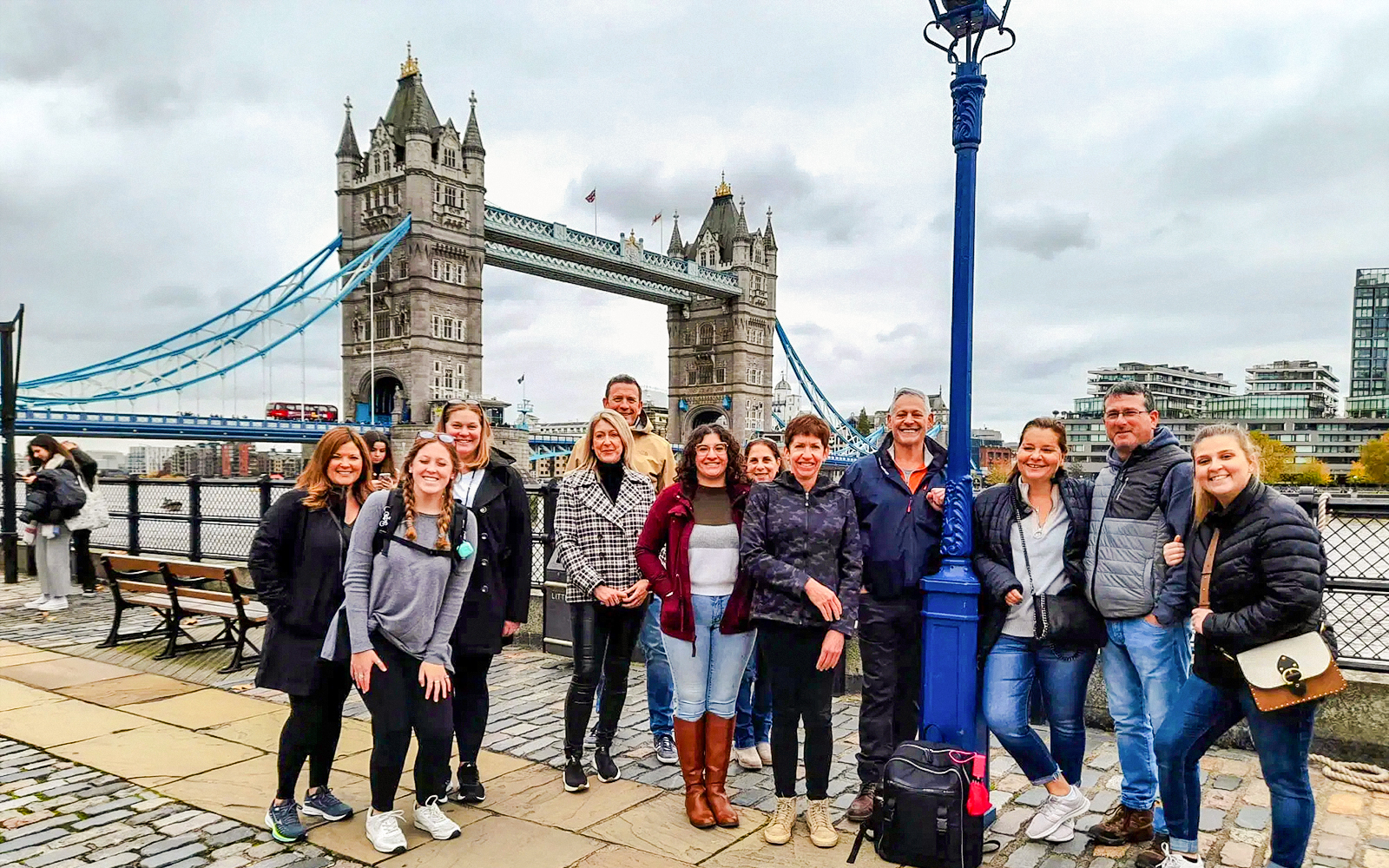 Group of tourists posing in front of Tower Bridge, London.