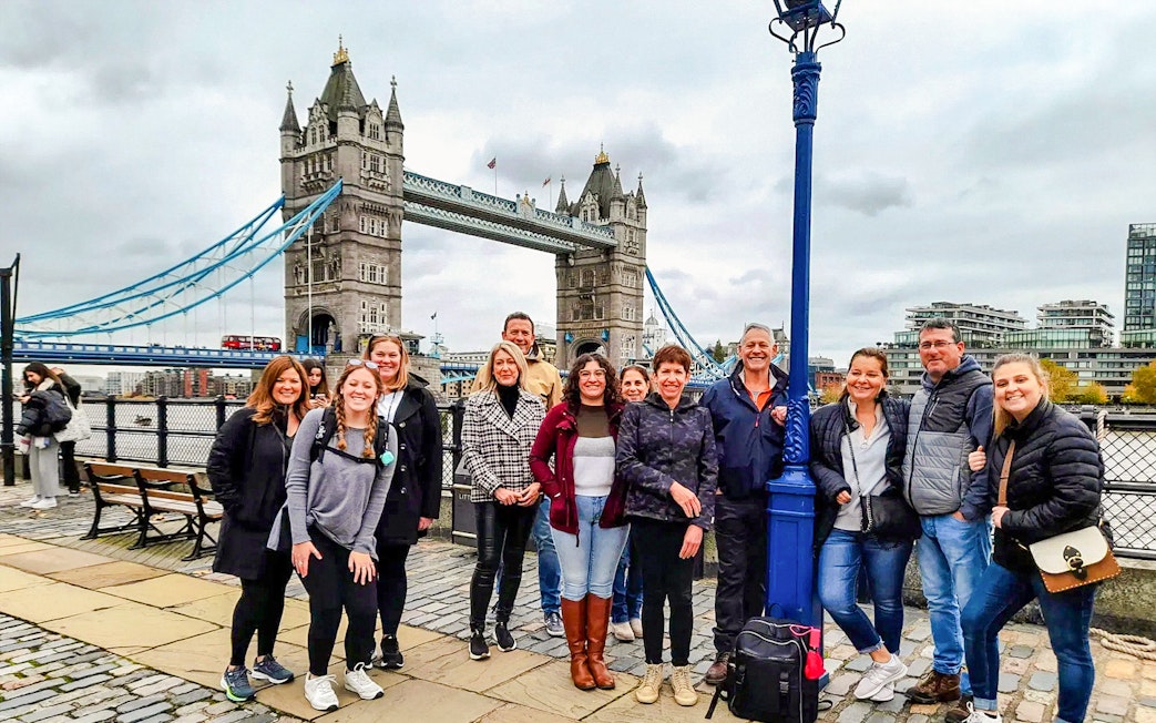 Group of tourists posing in front of Tower Bridge, London.