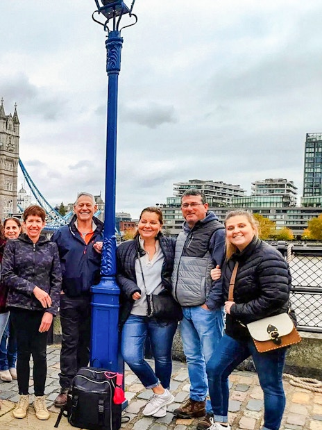 Group of tourists posing in front of Tower Bridge, London.