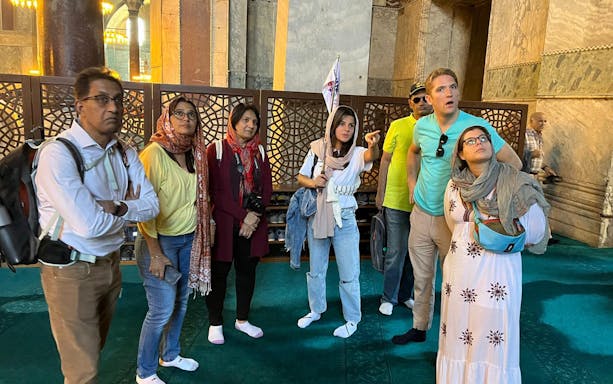 Tour group inside Hagia Sophia, Istanbul, with guide explaining historical details.