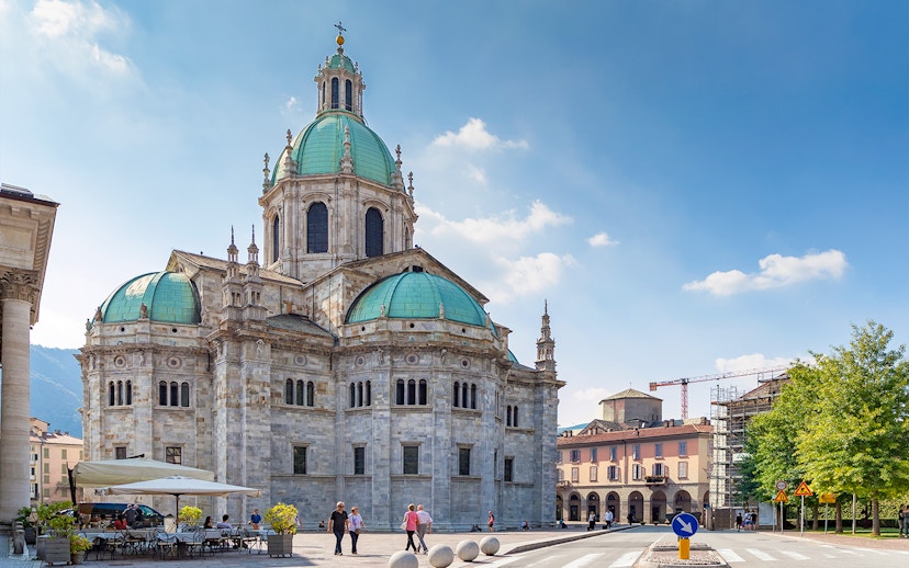 Como Cathedral with green domes and surrounding plaza in Como, Italy.