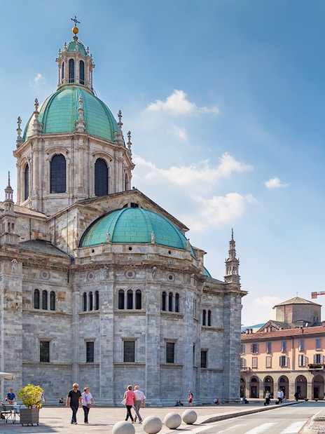 Como Cathedral with green domes and surrounding plaza in Como, Italy.