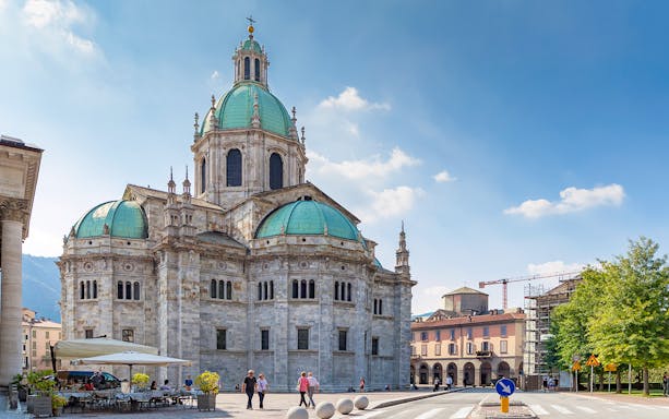 Como Cathedral with green domes and surrounding plaza in Como, Italy.