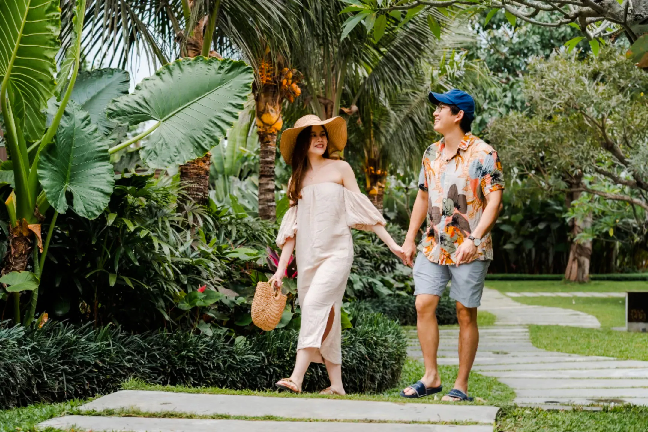 Couple walking through lush garden during professional photoshoot in Jakarta.
