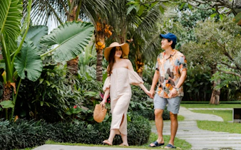 Couple walking through lush garden during professional photoshoot in Jakarta.