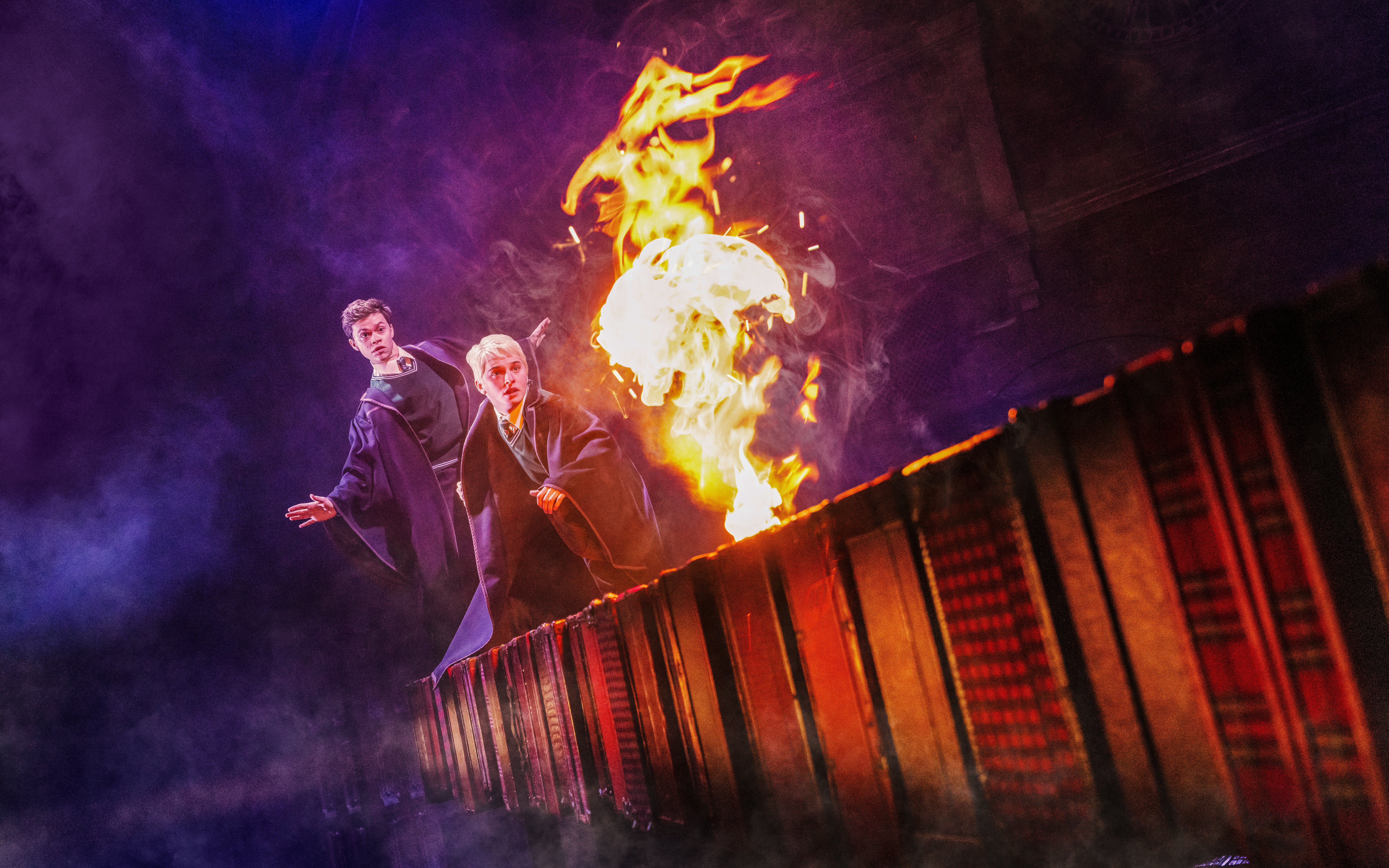 Two actors in wizard robes with fire on stage during Harry Potter and the Cursed Child, Broadway.