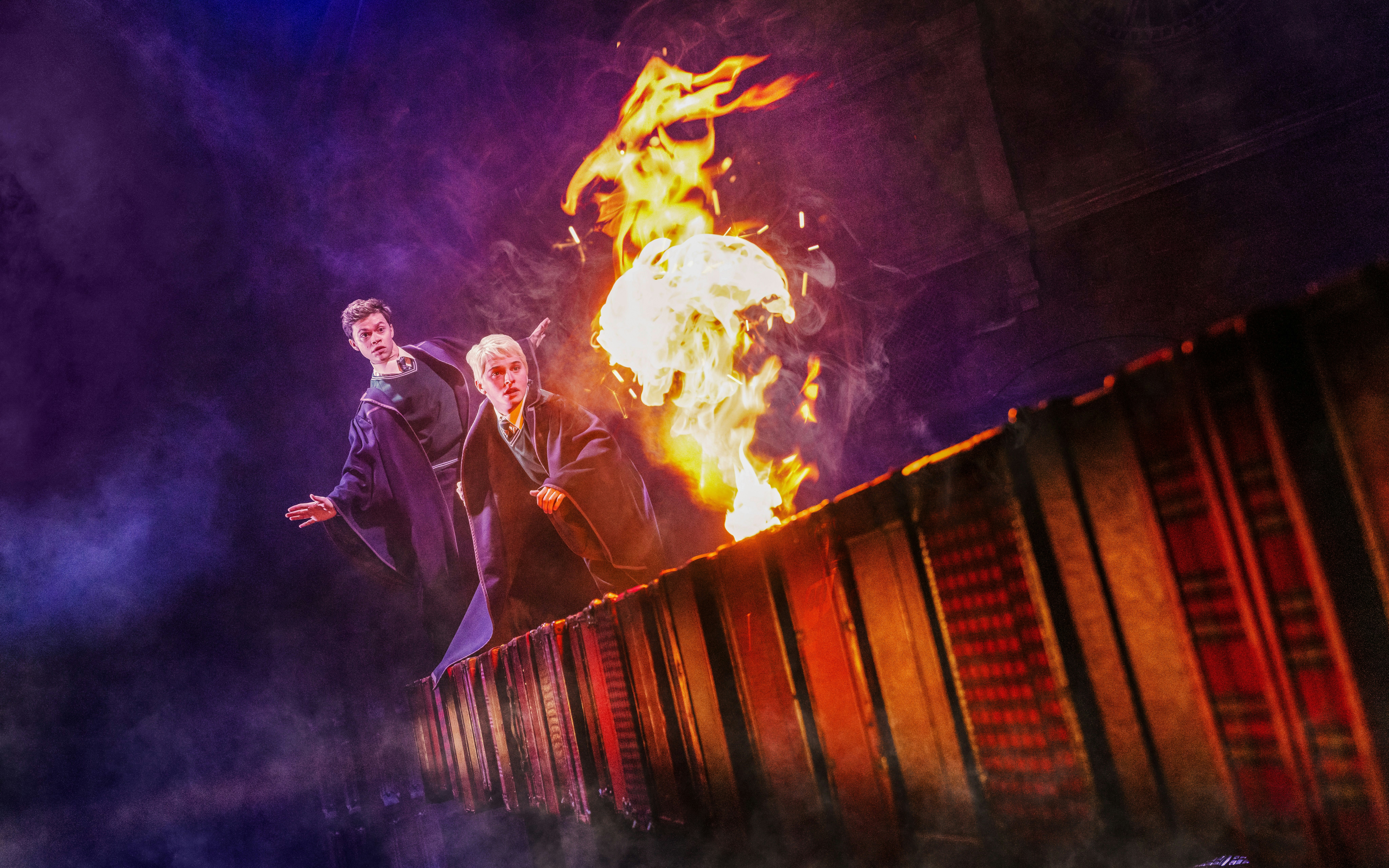 Two actors in wizard robes with fire on stage during Harry Potter and the Cursed Child, Broadway.