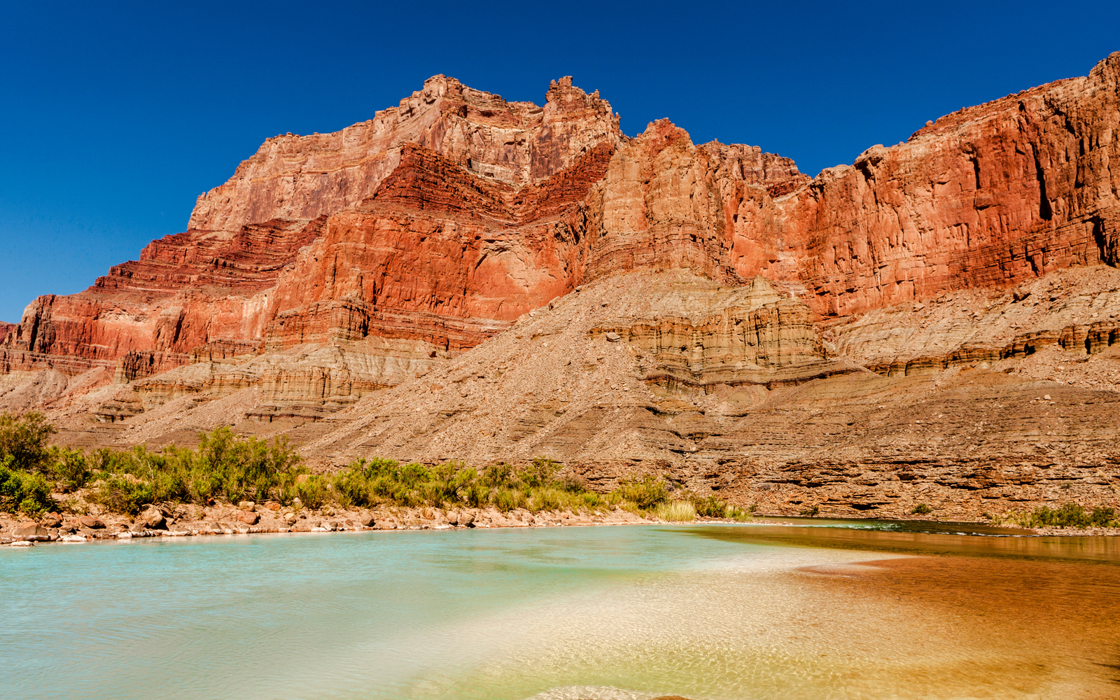Grand Confluence where Little Colorado River meets Colorado River, showcasing calcium carbonate-colored waters.