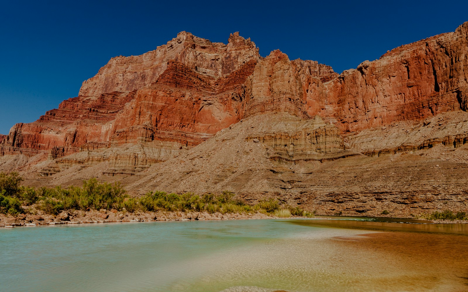 Grand Confluence where Little Colorado River meets Colorado River, showcasing calcium carbonate-colored waters.