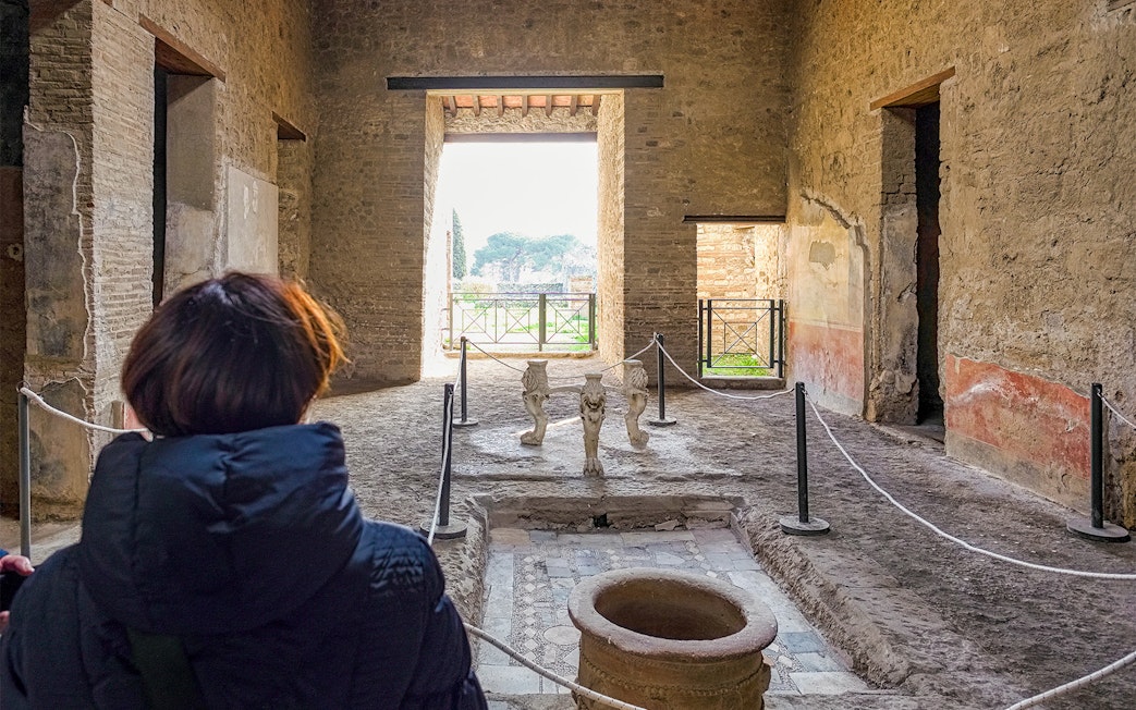 Tourists exploring the ancient Samnite House interior in Pompeii, Italy.