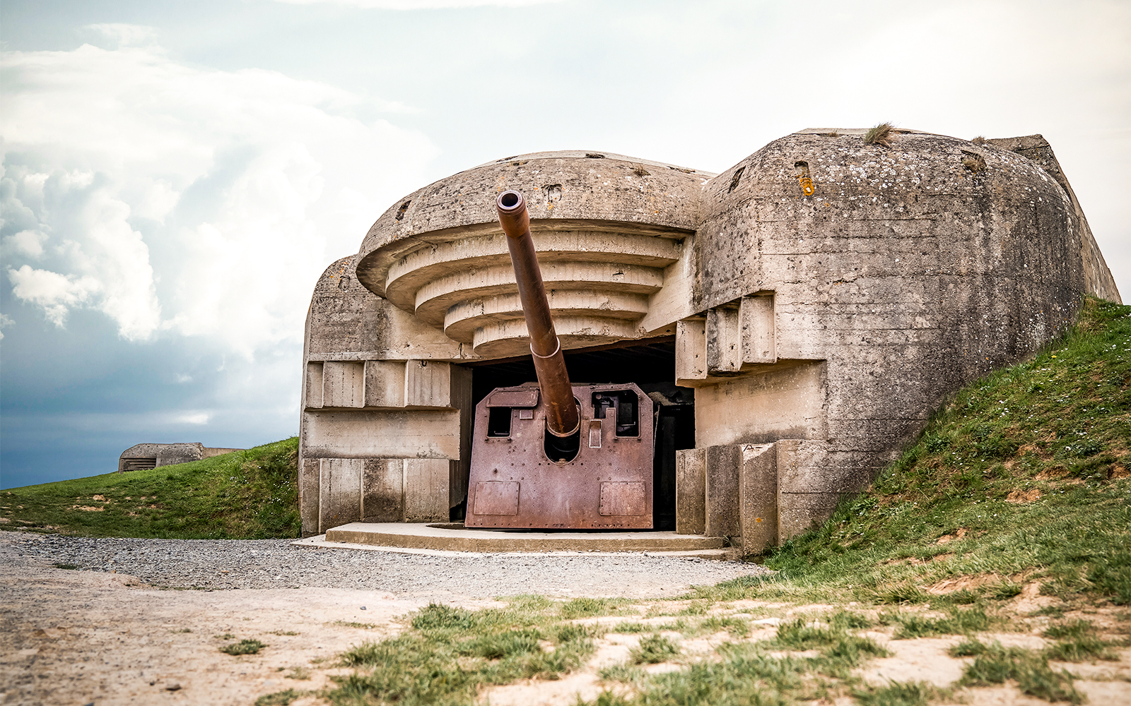Normandy D-Day Tour guide explaining historical site with visitors in front of Omaha Beach memorial.