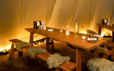 Cozy Sami tent interior with wooden table and benches, Tromso Northern Lights tour.