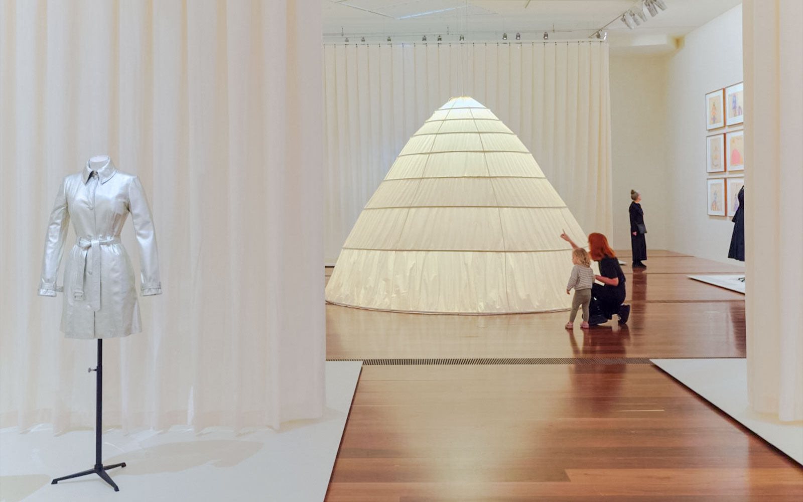 Exhibit of a silver coat and large cone structure at Martin Grant Exhibition.