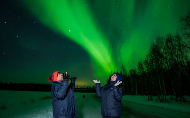 Couple enjoying Northern Lights in Rovaniemi, Finland.