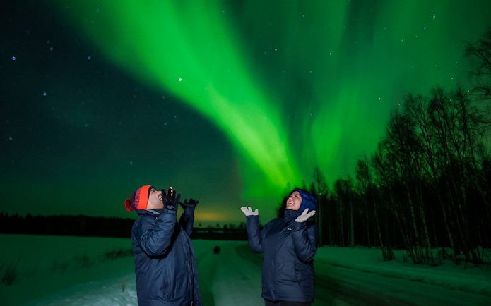 Couple enjoying Northern Lights in Rovaniemi, Finland.