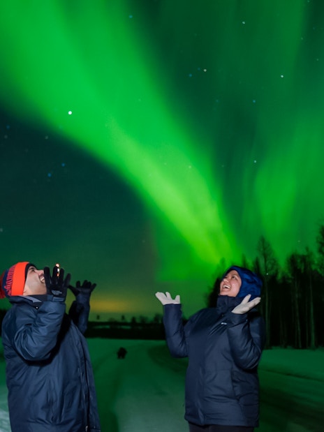 Couple enjoying Northern Lights in Rovaniemi, Finland.
