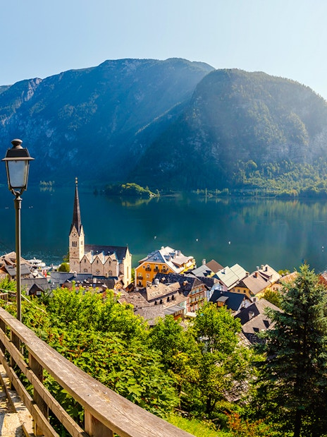 Pathway overlooking Hallstatt village and Lake Hallstatt, Austria, with mountains in the background.