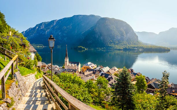 Pathway overlooking Hallstatt village and Lake Hallstatt, Austria, with mountains in the background.
