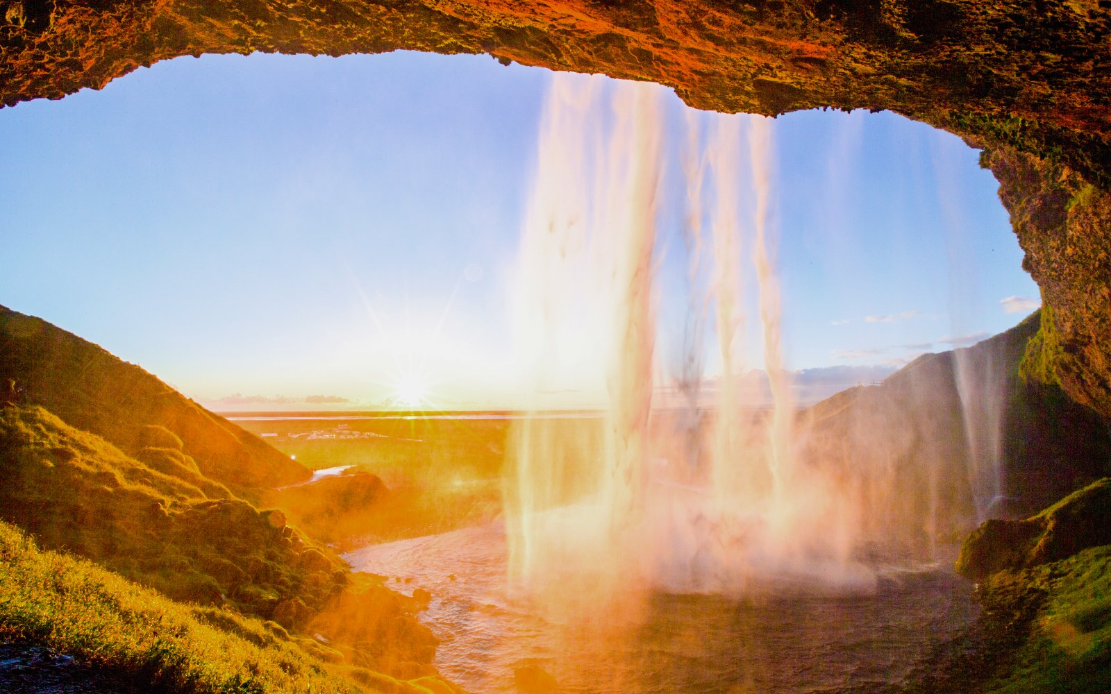 Seljalandsfoss waterfall in Iceland with sunset view from behind the cascade.