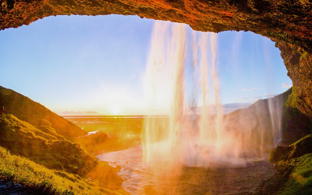 Seljalandsfoss waterfall in Iceland with sunset view from behind the cascade.