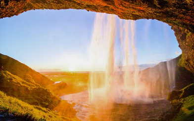 Seljalandsfoss waterfall in Iceland with sunset view from behind the cascade.