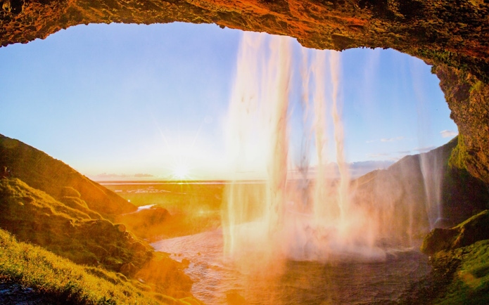Seljalandsfoss waterfall in Iceland with sunset view from behind the cascade.