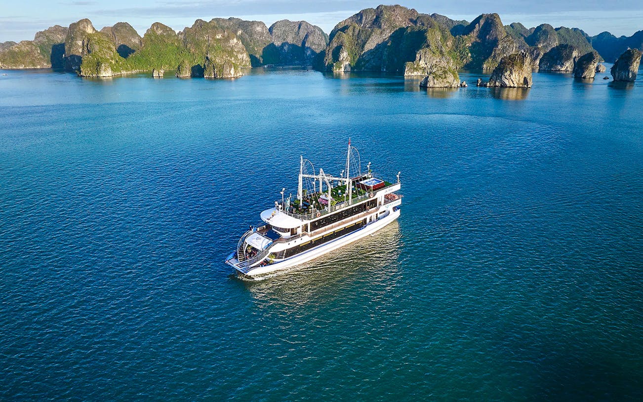 Tour boat sailing in Ha Long Bay, Vietnam, with limestone islands in the background.