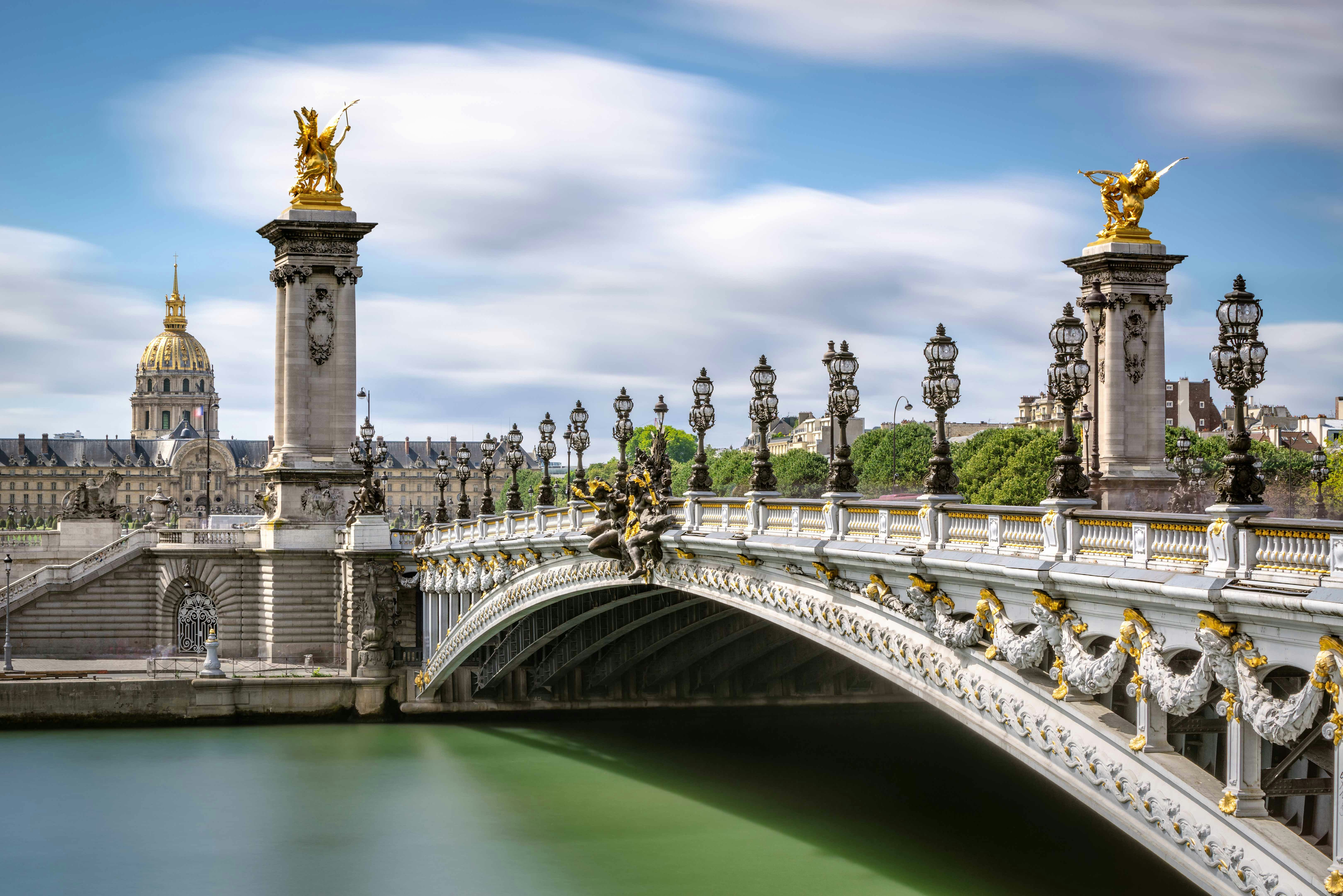 Pont Alexandre III bridge over the Seine River in Paris with ornate lampposts and sculptures.