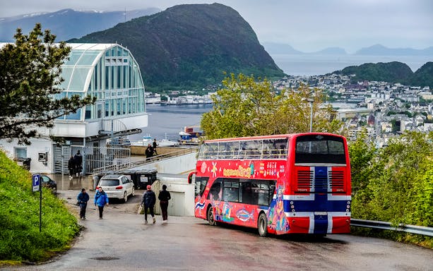 Alesund hop-on hop-off bus near scenic viewpoint overlooking city and fjord.