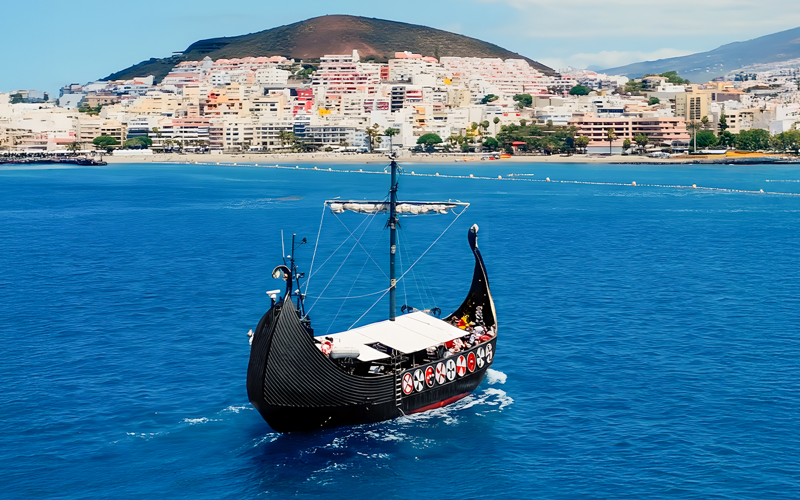 Viking boat sailing with cityscape in background on whale and dolphin watching cruise.