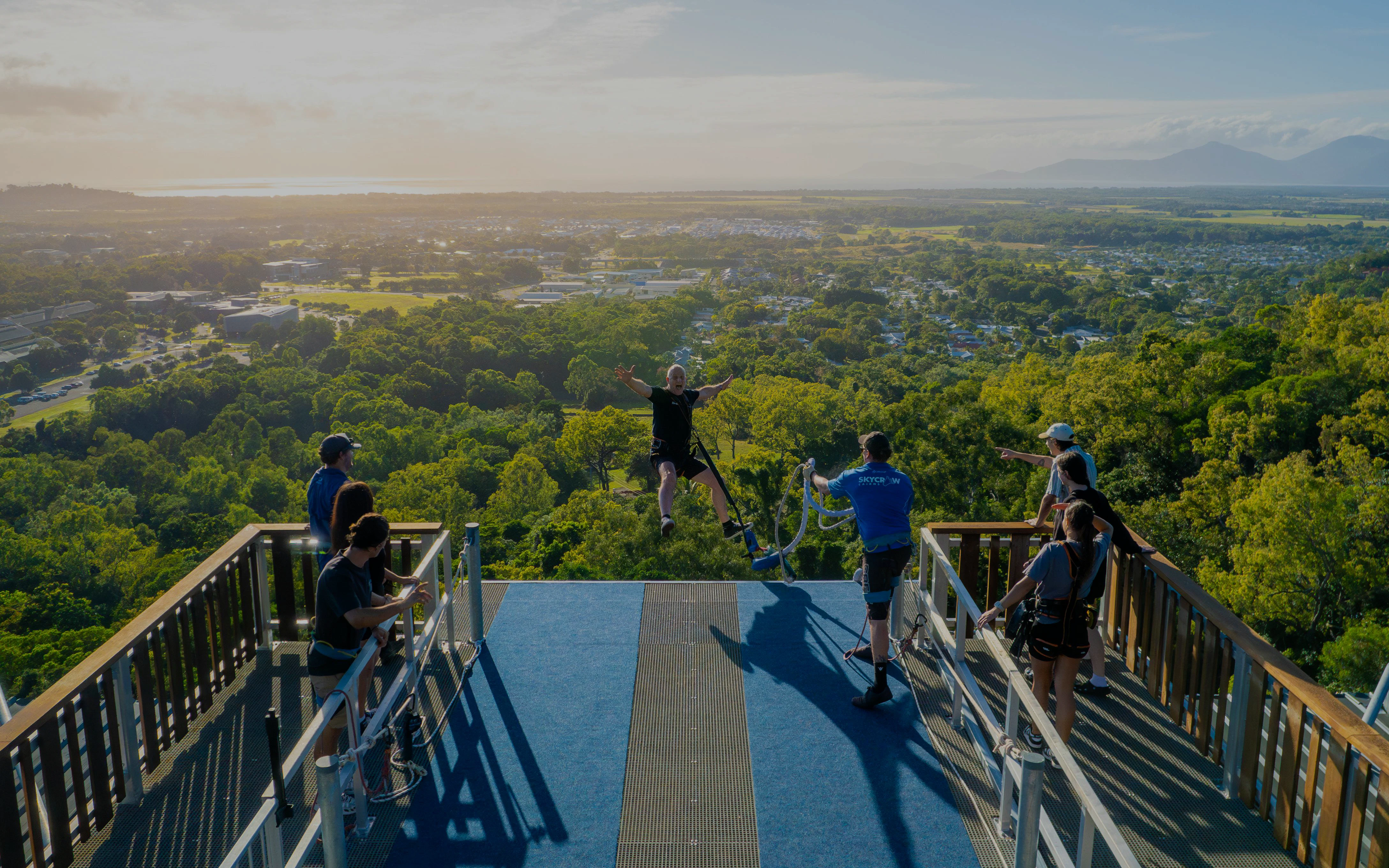 Visitor bungee jumping from Skypark Cairns platform at sunrise with scenic view.