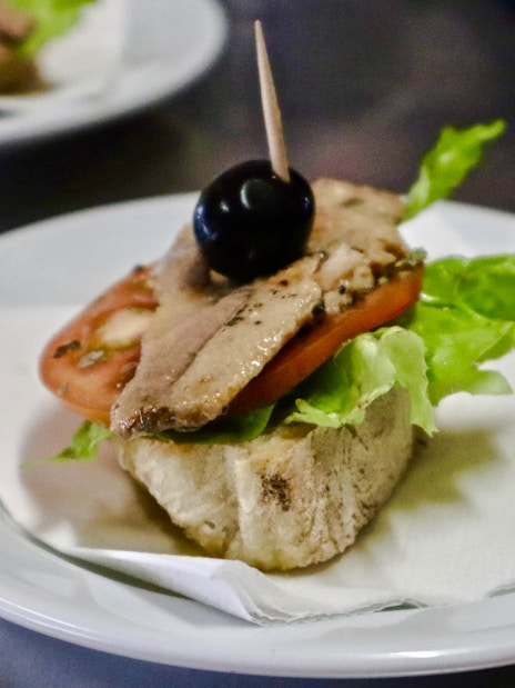 Open-faced sandwich with lettuce, tomato, fish, and olive on a Lisbon food tour.