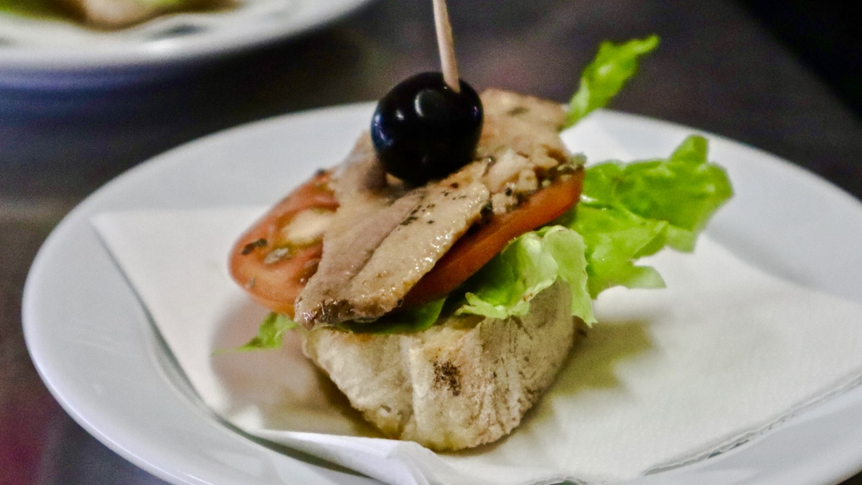 Open-faced sandwich with lettuce, tomato, fish, and olive on a Lisbon food tour.